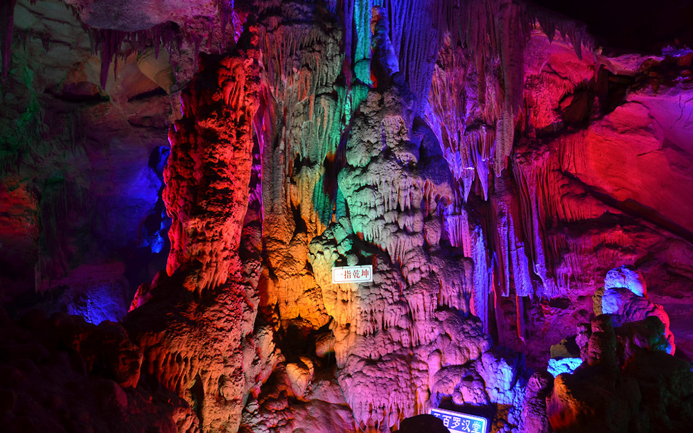 Multi-colored LED lights illuminating a cave formation at Dongjiang Lake.